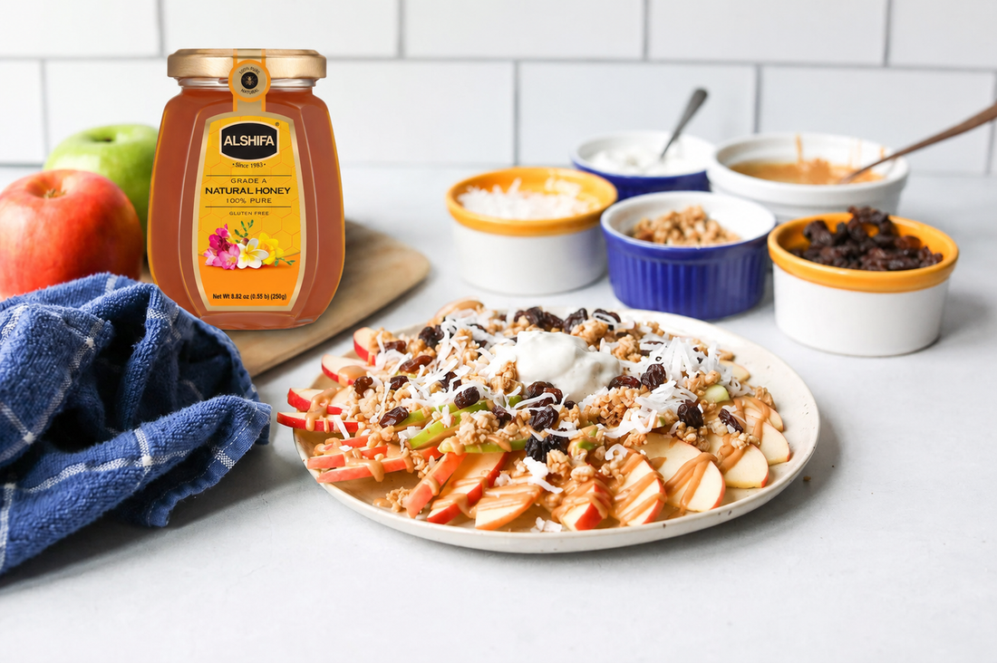 Apple nachos with sliced apples, granola, coconut, raisins, and peanut butter drizzle beside a jar of ALSHIFA Natural Honey