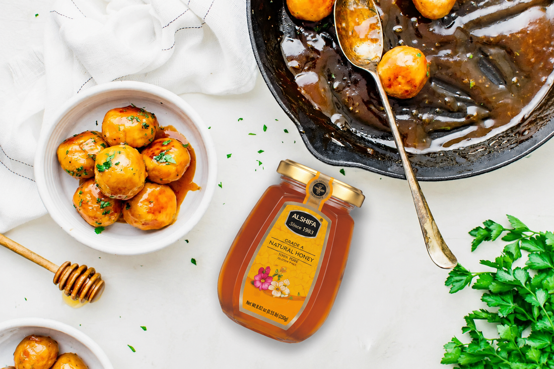 Hot honey chicken meatballs in glaze, garnished with parsley, beside a jar of ALSHIFA Natural Honey