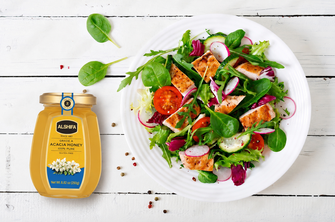 Green salad with grilled chicken, tomatoes, and radish beside a jar of ALSHIFA Acacia Honey