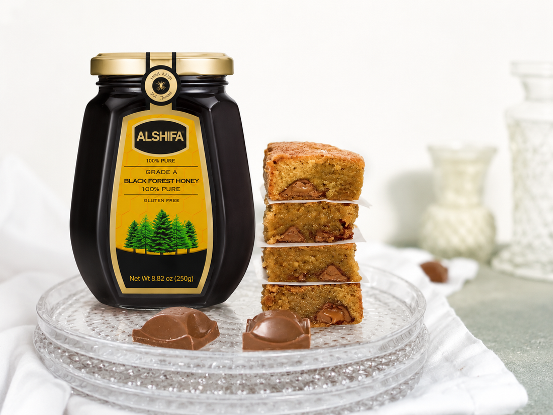 Stack of honey brown butter blondies with chocolate chunks beside a jar of ALSHIFA Black Forest Honey