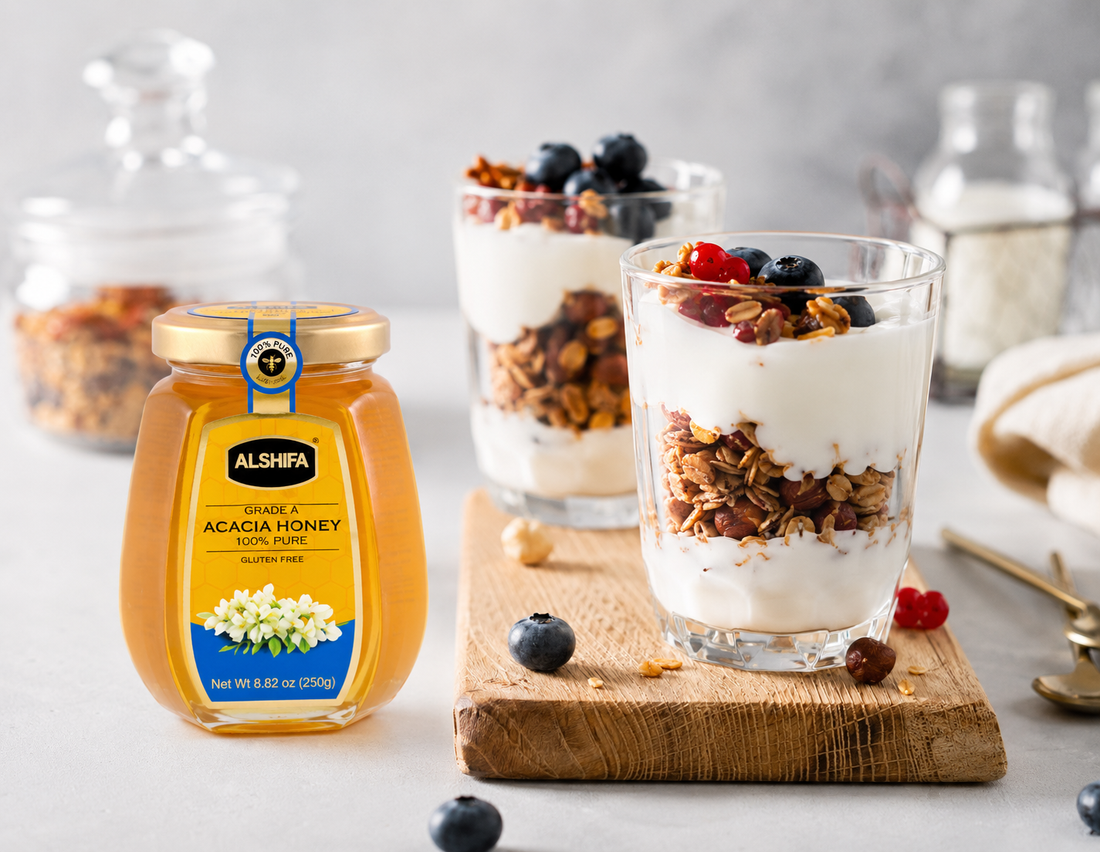 Honey-yogurt breakfast parfaits layered with granola and blueberries beside a jar of ALSHIFA Acacia Honey
